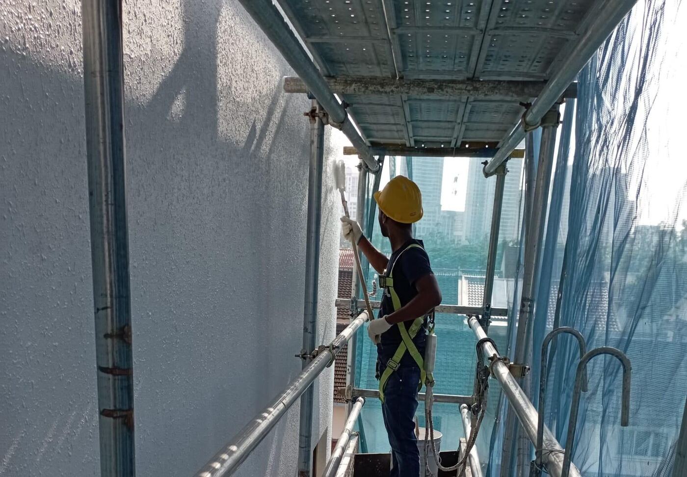 Technician carrying out external façade painting and sealant repair in Singapore